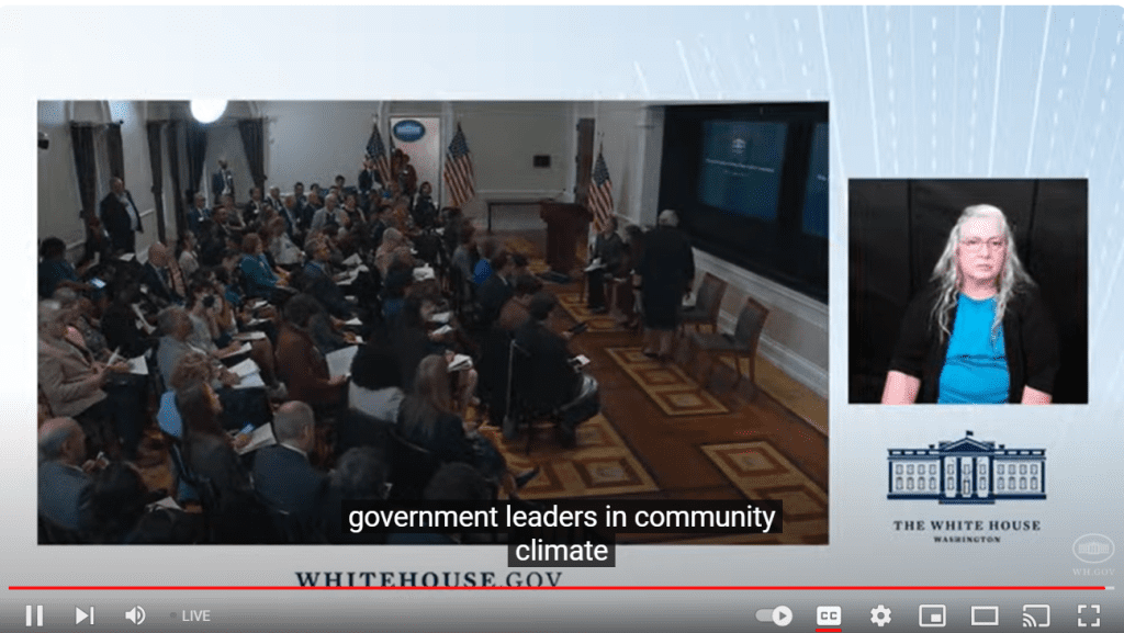 Audience and sign language interpreter in a White House conference room