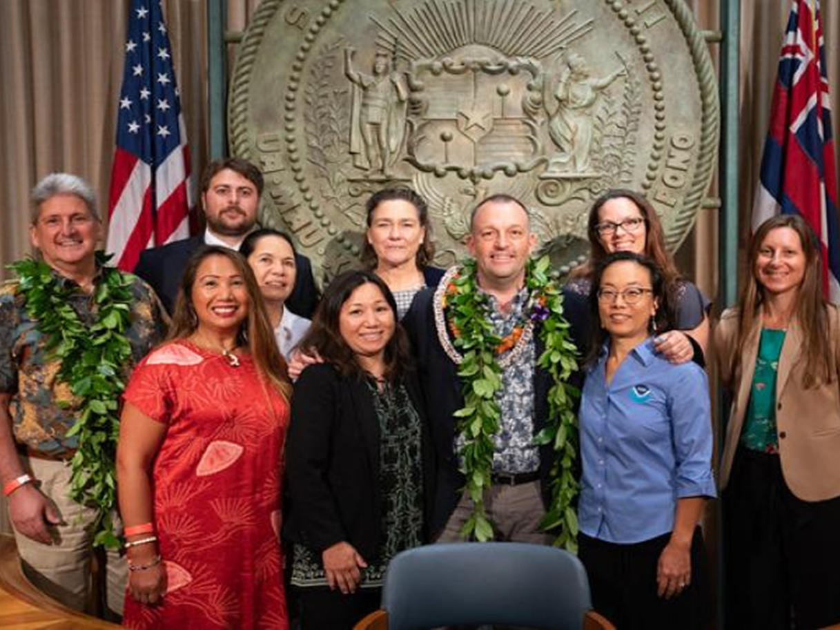 A diverse group of One Health professionals joined Josh Green, Governor of the state of Hawaiʻi, for the Hawaiʻi One Health Month Proclamation signing ceremony, February 6, 2023. Left to Right: Back: Neil Vizeau, USDA; Sandra Chang University of Hawaiʻi, John A. Burns School of Medicine; Stephanie Kendrick, Hawaiian Humane Society; Stacie Robinson, NOAA Fisheries; Front: David Lassner UH President, Julie Bennington VCA Veterinary Clinic, Jenee Odani UH College of Tropical Agricultural and Human Resources, Josh Green, Governor of the state of Hawaiʻi, Kirsten Leong, NOAA Fisheries; Michelle Barbieri, NOAA Fisheries.
