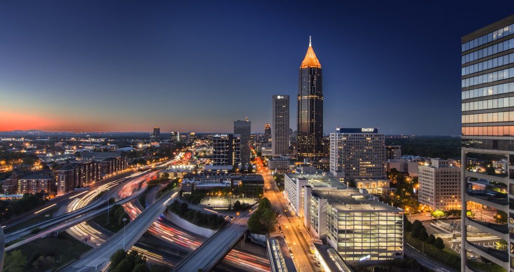 Against a dark blue sky, roads and tall building are lit in yellow