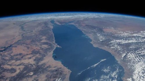 A portion of the Earth seen from space. A blue body of water is in the center of the image, surrounded to the left and right by brown land.